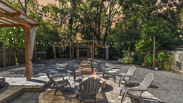 An outdoor patio with a fire pit, seating, and string lights. - Downtown Jacksonville Retreat Pet-friendly With Hot Tub & Backyard Oasis (Jacksonville)