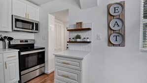 A modern kitchen with white cabinetry, stainless steel appliances, and a central island with drawers. - Downtown Jacksonville Retreat Pet-friendly With Hot Tub & Backyard Oasis (Jacksonville)