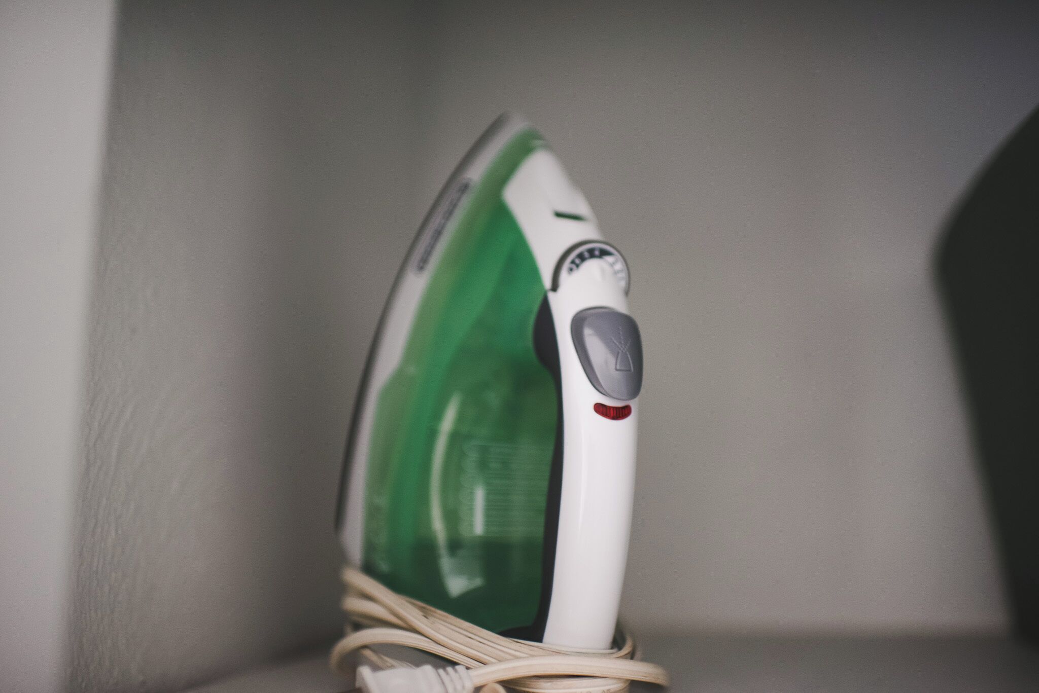 An iron with a cord plugged in, placed on a surface.