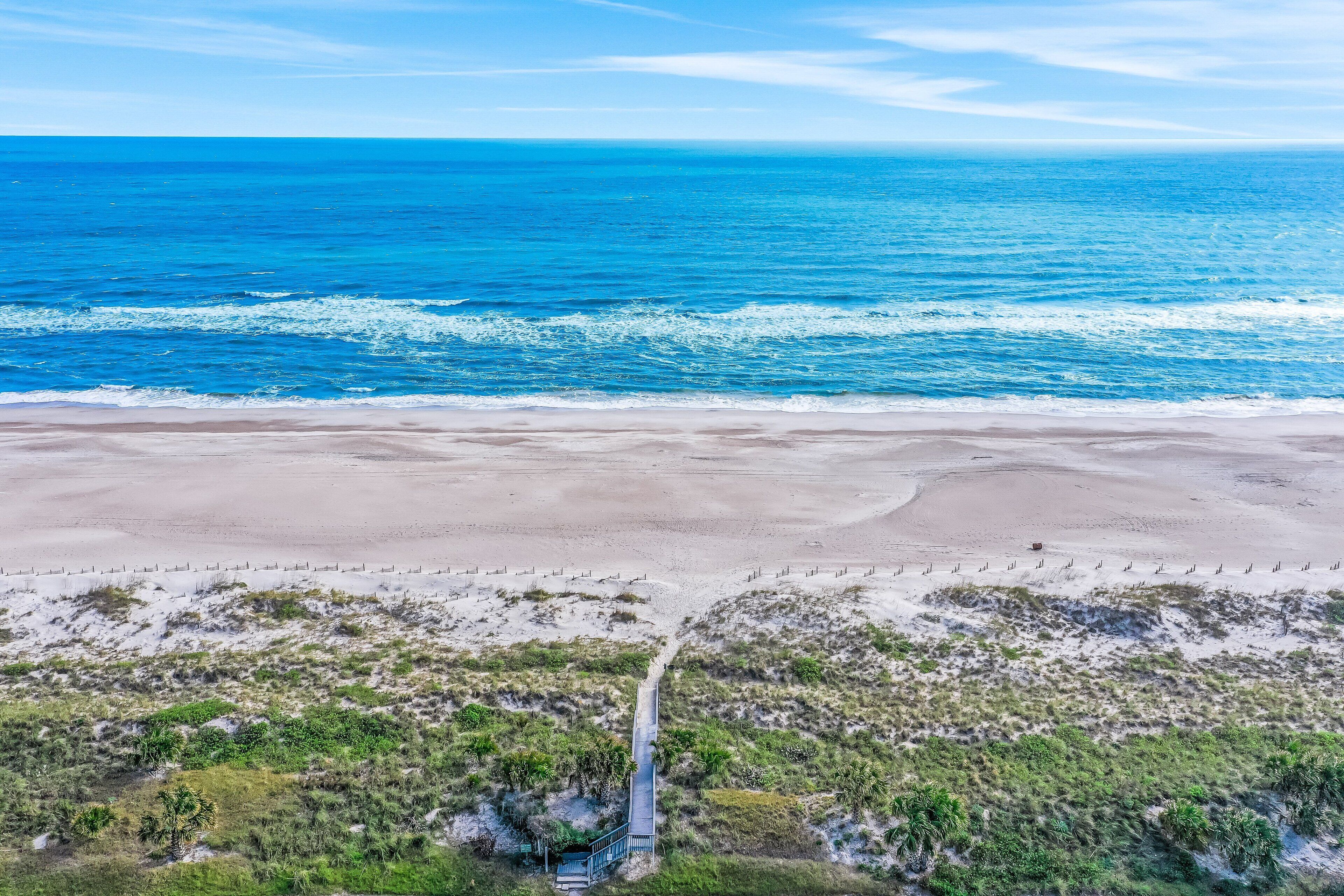 An aerial view of a beach with a pathway leading to a structure.
