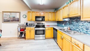 A kitchen with wooden cabinets, stainless steel appliances, a tiled backsplash, and a window with a view. - Serene Home With Enclosed Yard, Grill, Games, & Central AC - Dog-friendly (St. Augustine)