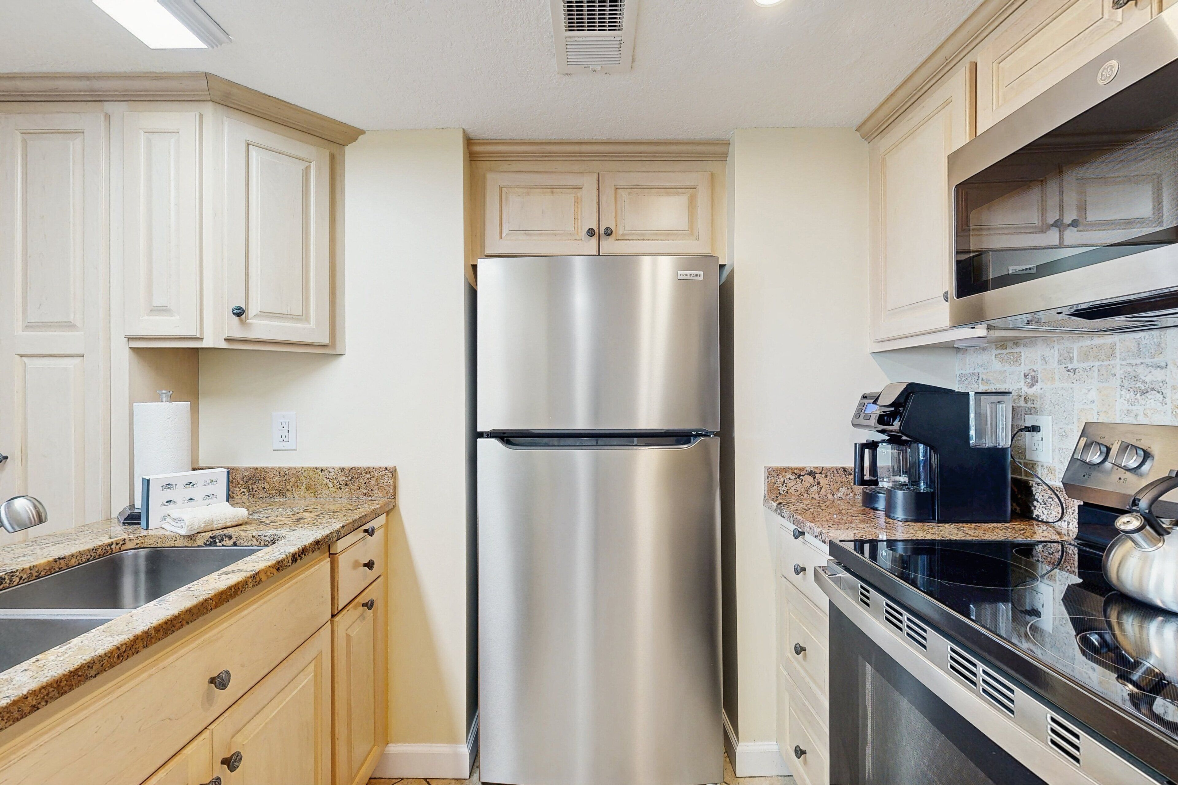 A kitchen with a stainless steel refrigerator, a built-in oven, and a coffee maker.