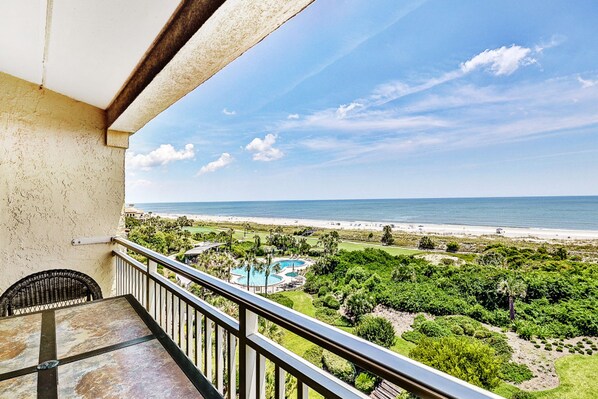 Un balcon avec vue sur une plage et une piscine.