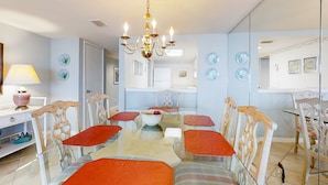 A dining area with a glass table, red cushioned chairs, and a chandelier. - Oceanfront Condo With Spacious Balcony, Great Views, AC & Outdoor Pooloc (Fernandina Beach)