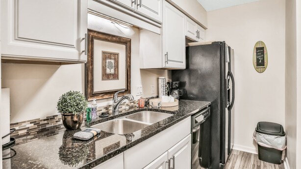 A kitchen with white cabinets, a black refrigerator, a sink, and a trash can. - Quiet Coastal Escape Within Walking Distance to Beach With Shared Pool (Fernandina Beach)