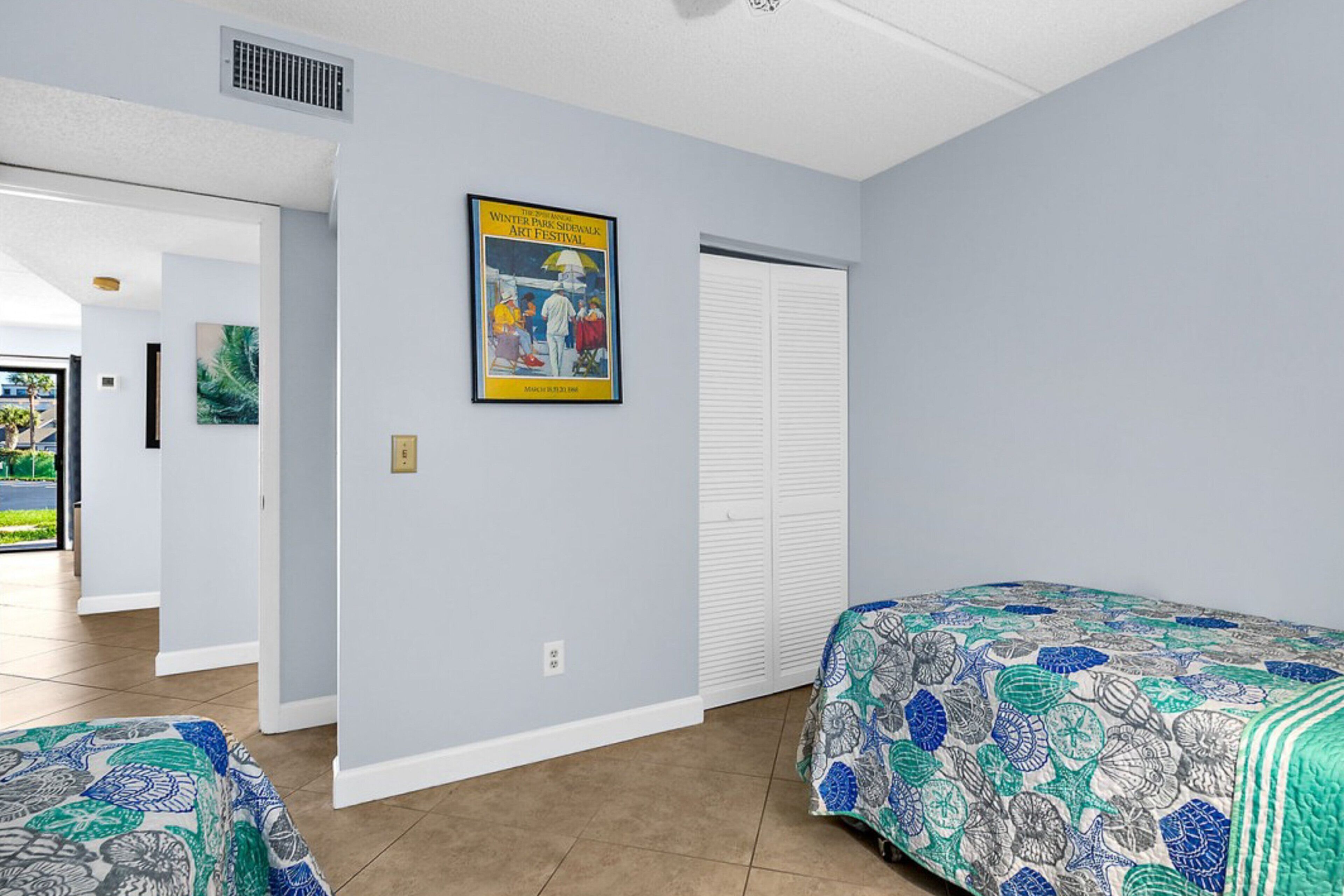 A hotel room with two beds, a poster on the wall, and a door leading to a balcony.