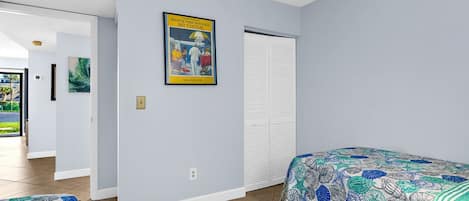 A hotel room with two beds, a poster on the wall, and a door leading to a balcony.