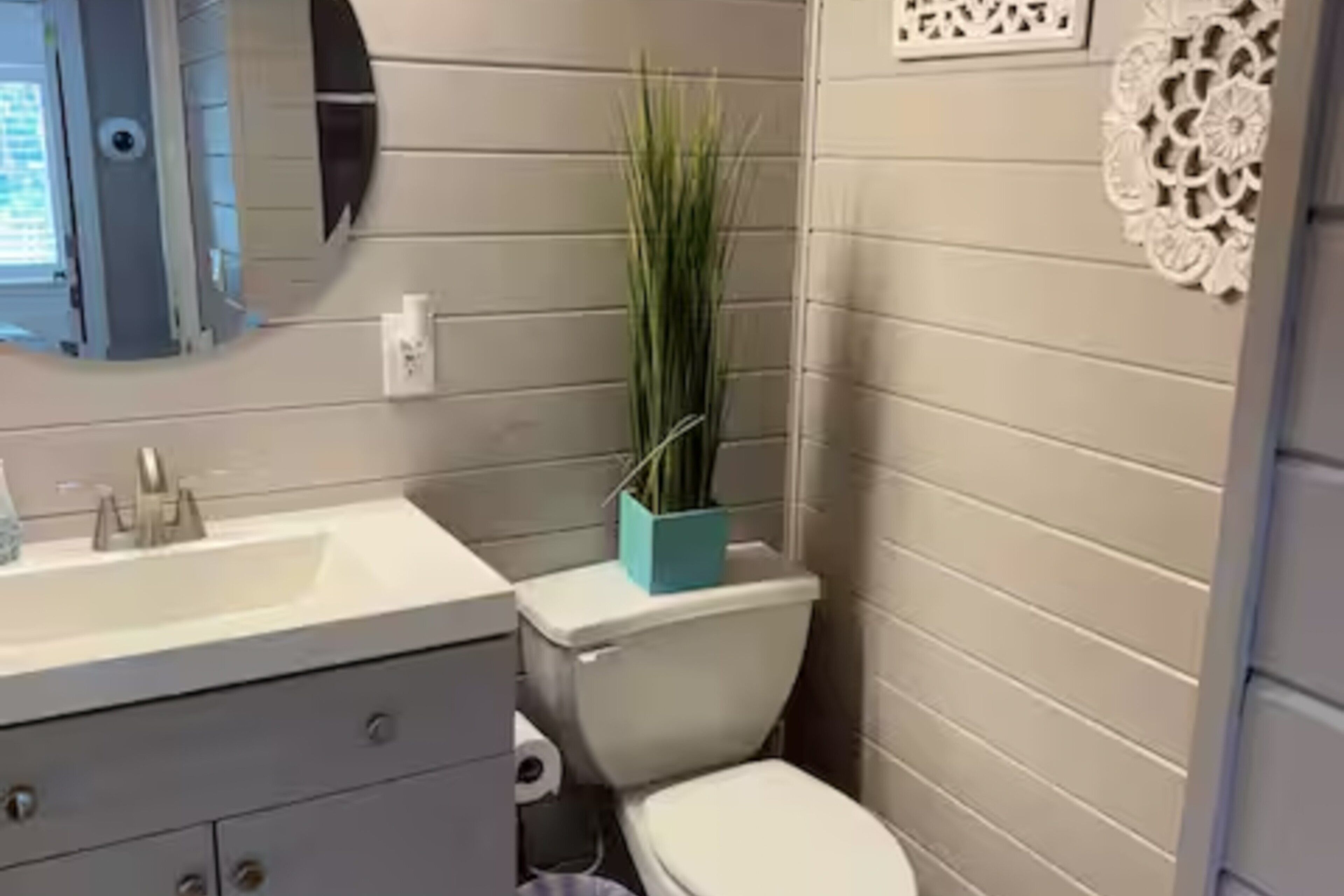 A bathroom with a white sink, a toilet, and a mirror.