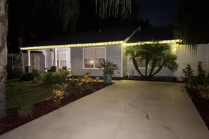 A house with a concrete driveway, a front porch, and a well-lit exterior. - Spacious Coastal Home in St. Augustine Pool, Outdoor Oasis & Private Suite (St. Augustine)