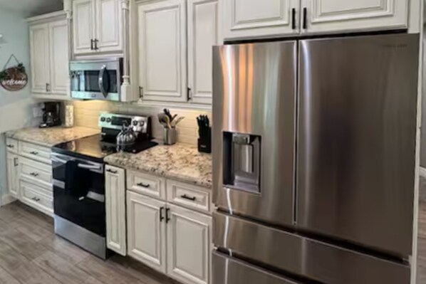 A modern kitchen with white cabinetry, stainless steel appliances, and a granite countertop. - Spacious Coastal Home in St. Augustine Pool, Outdoor Oasis & Private Suite (St. Augustine)