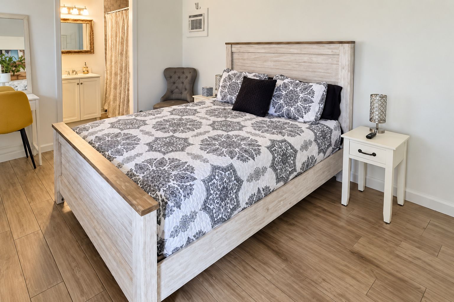 A bedroom with a wooden bed, a bedside table, a chair, a desk, and a mirror.