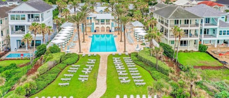 Ein Resort mit einem zentralen Pool, mehreren Gästezimmern und einer gepflegten Rasenfläche mit Liegestßhlen.