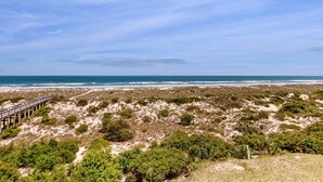 A coastal landscape with a wooden boardwalk leading to the beach, surrounded by dunes and sparse vegetation. - Oceanfront Condo With Great Ocean View, Balcony, Fast Wifi & 2 Shared Pools (Fernandina Beach)