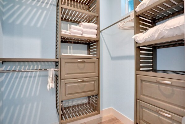 A walk-in closet with multiple shelves, drawers, and hanging space, featuring neatly folded towels and a metal rack. - Palm-surrounded Stunner With Enclosed Pool & Water Views - Dog-friendly (Palm Coast)