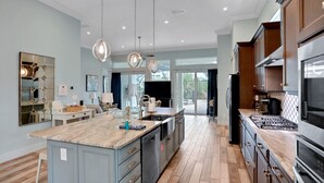A spacious kitchen with a large island, modern appliances, and pendant lighting. - Palm-surrounded Stunner With Enclosed Pool & Water Views - Dog-friendly (Palm Coast)