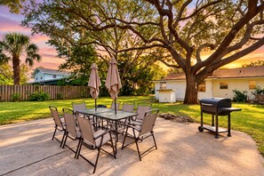 An outdoor patio with a table and chairs, surrounded by trees and a barbecue grill. - Spacious Pet -friendly Home w/ Fenced in Yard and Close to The Beach (St. Augustine)