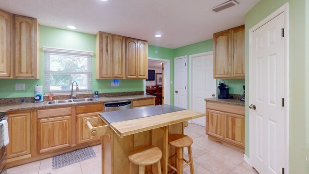 A kitchen with wooden cabinets, a stainless steel countertop, and a bar stool area. - Spacious Pet -friendly Home w/ Fenced in Yard and Close to The Beach (St. Augustine)
