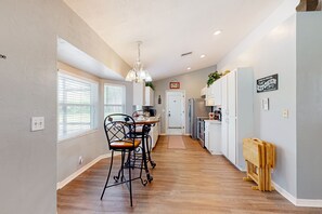 Una cocina moderna con comedor, suelo de madera y una araña.
