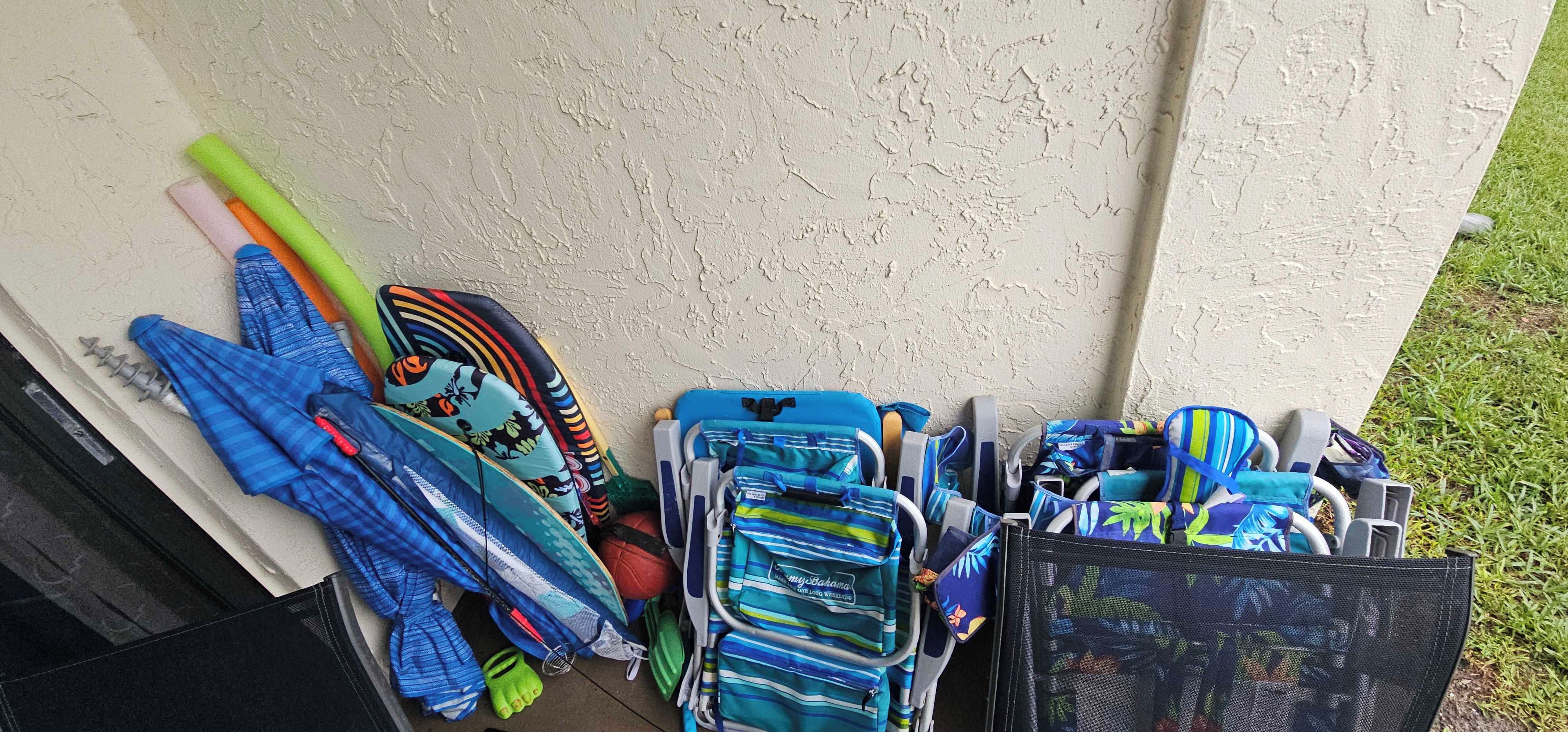 A collection of colorful bags and umbrellas leaning against a wall.
