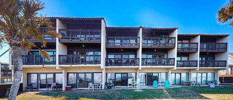 A multi-story hotel with balconies, outdoor seating, and a well-maintained lawn.