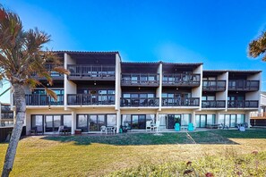 Ein mehrstöckiges Hotel mit Balkonen, Sitzgelegenheiten im Freien und einem gepflegten Rasen.