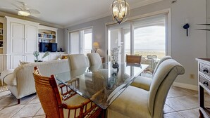 Un'ampia zona giorno con tavolo da pranzo in vetro, posti a sedere confortevoli e vista panoramica attraverso ampie finestre.