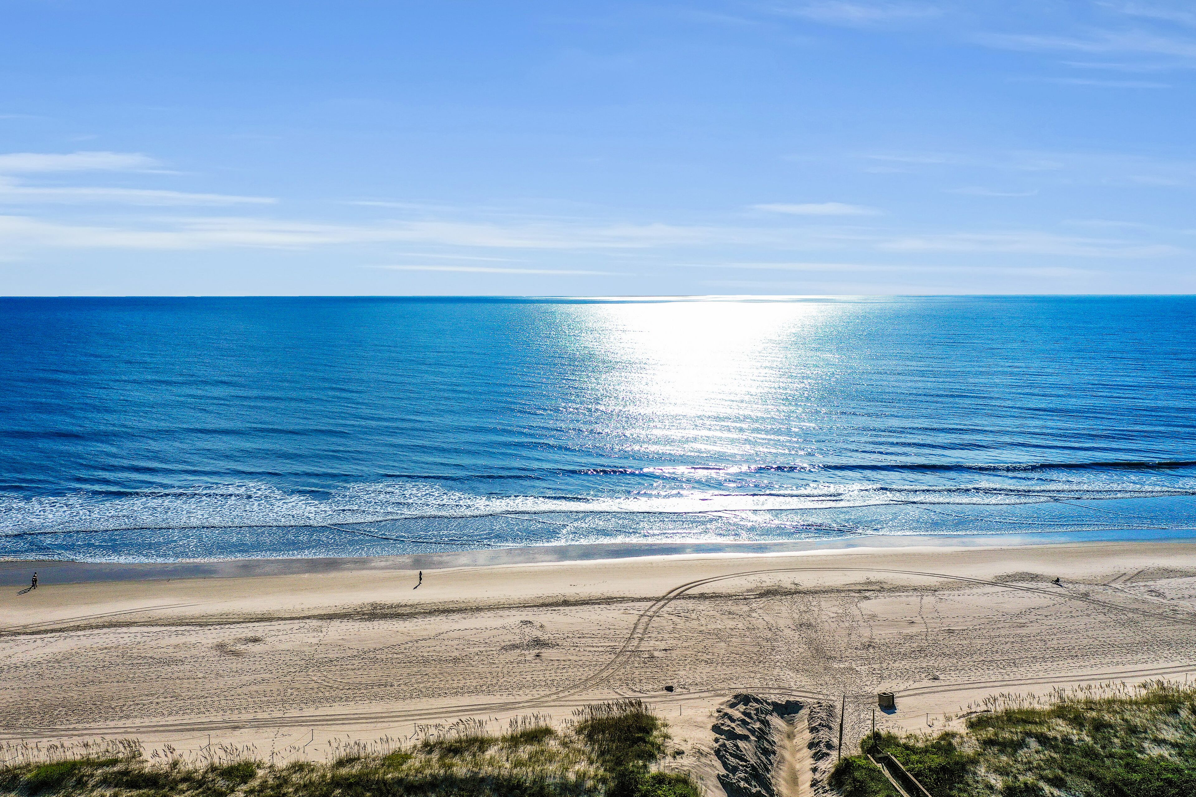Une plage avec un ciel dégagé, une mer calme et un rivage sablonneux.