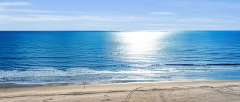 Une plage avec un ciel dégagé, une mer calme et un rivage sablonneux.