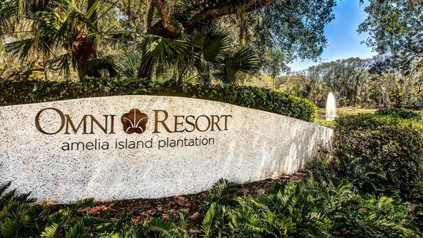 A sign for Omni Resort Amelia Island Plantation with lush greenery and a fountain in the background. - Oceanview Condo in Amelia Island Plantation With Balcony & Pool (Fernandina Beach)