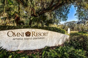 Une enseigne indiquant l’emplacement du complexe Omni Resort Amelia Island Plantation, avec une végétation luxuriante et une fontaine en arrière-plan.