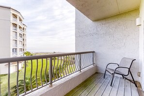 Ein Balkon mit Metallgeländer, einem Stuhl und Blick auf ein Gebäude sowie Grünflächen.