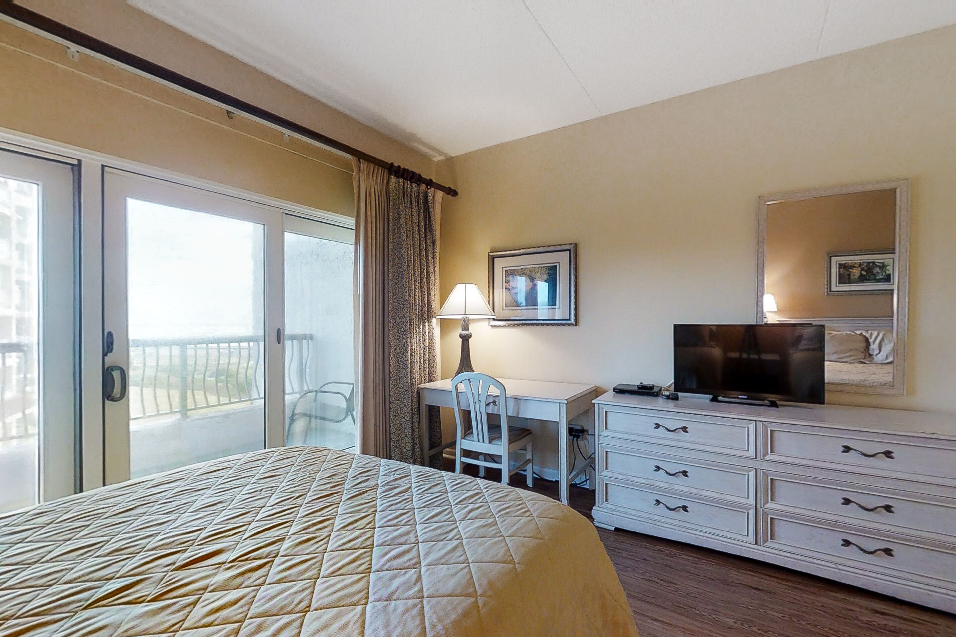 Une chambre d’hôtel équipée d’un lit, d’un bureau, d’une chaise, d’une télévision et d’une commode.