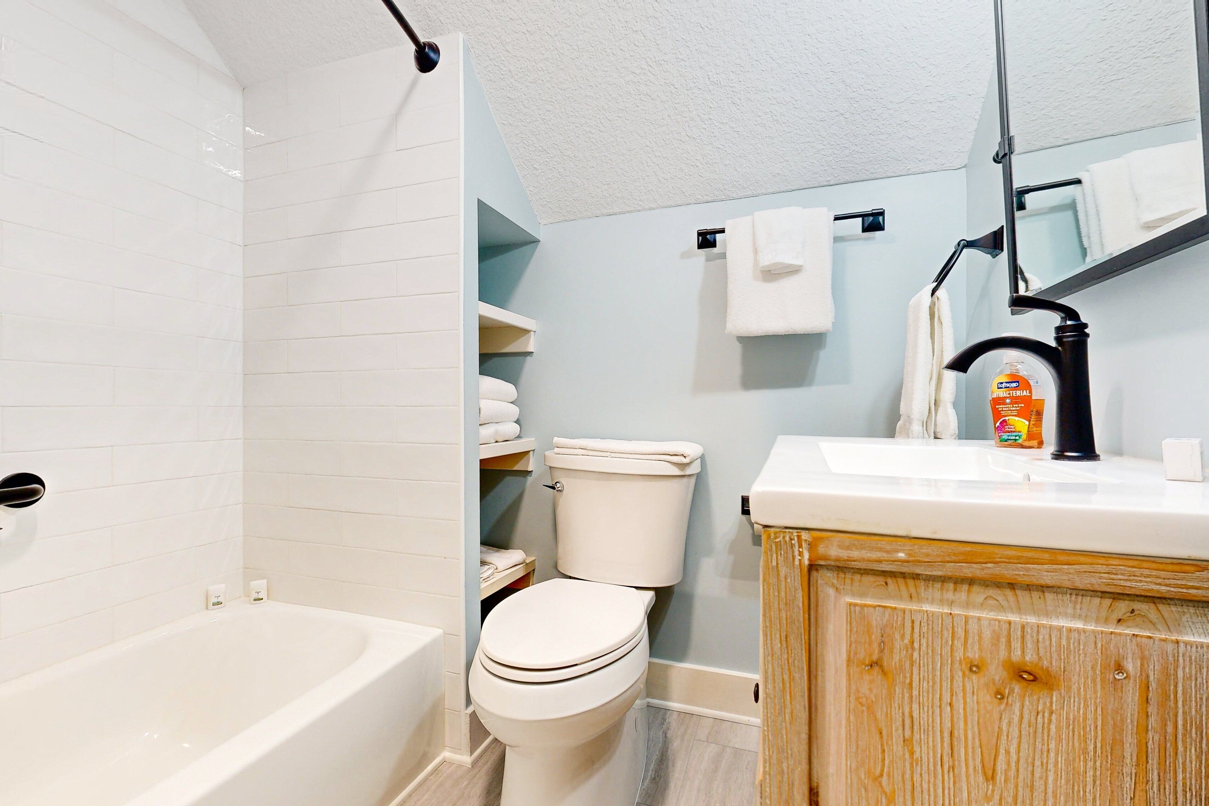 A bathroom with a bathtub, toilet, and vanity with a mirror.