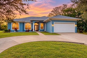A two-story house with a garage, a front entrance, and a well-maintained lawn. - Prime House With Lanai, Private Pool, Bbq, and Water Views (Palm Coast)