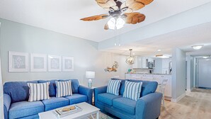 A modern living room with two blue sofas, a white coffee table, and a ceiling fan. - Oceanfront Rental With Amazing Views, Beach Access, Pools, Tennis & Pickleball (St. Augustine)