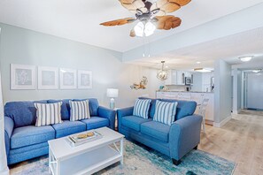 A modern living room with two blue sofas, a white coffee table, and a ceiling fan. - Oceanfront Rental With Amazing Views, Beach Access, Pools, Tennis & Pickleball (St. Augustine)