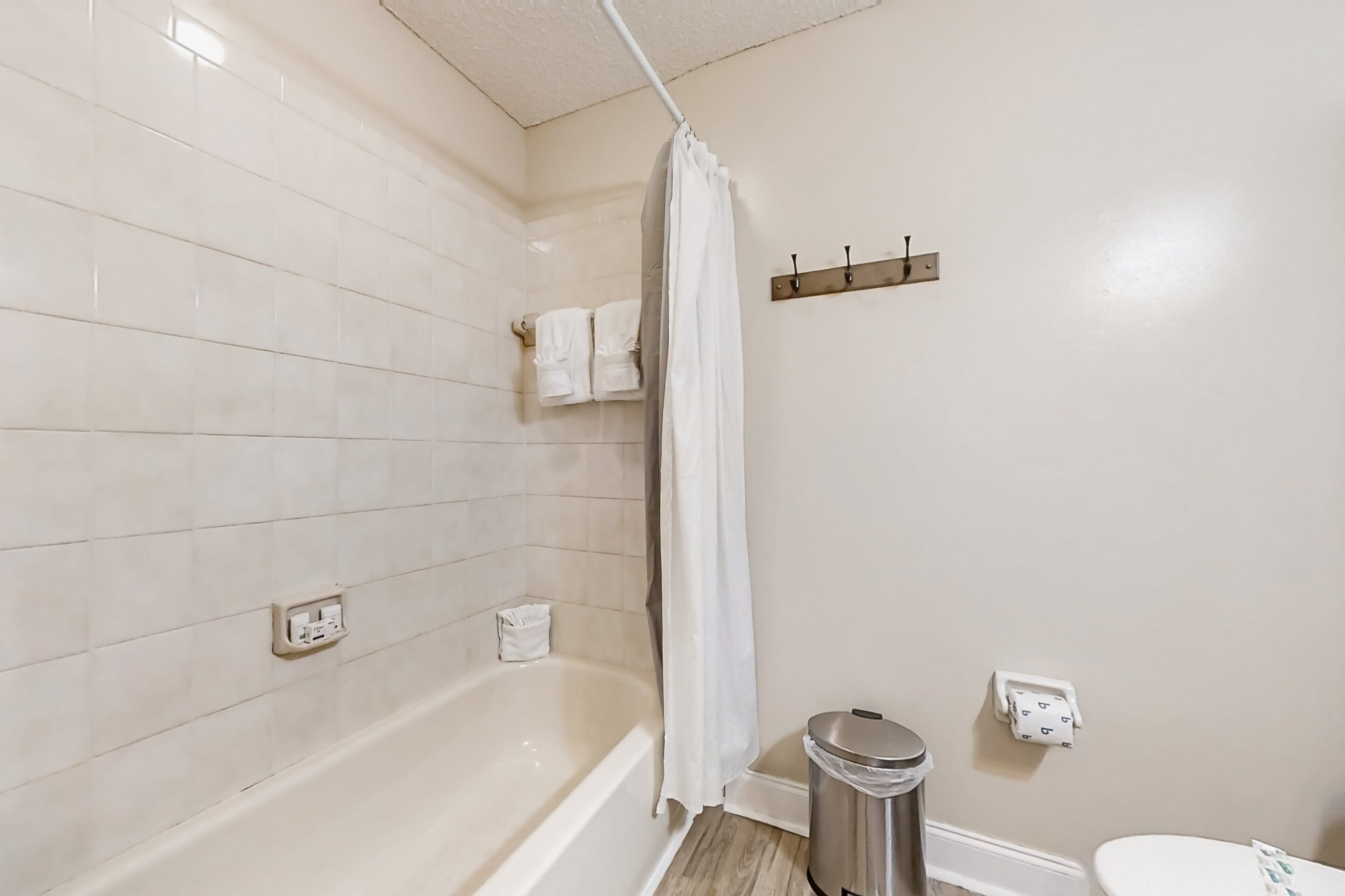 A bathroom with a bathtub, a toilet, and a trash can.