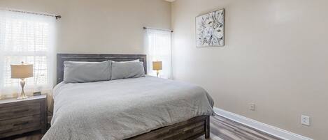 A bedroom with a bed, nightstands, a ceiling fan, and a window with curtains.