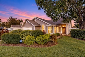 A residential house with a garage, surrounded by well-maintained lawns and hedges, under a twilight sky. - Spacious and Quiet Home With Private Patio & Enclosed Yard (Jacksonville)