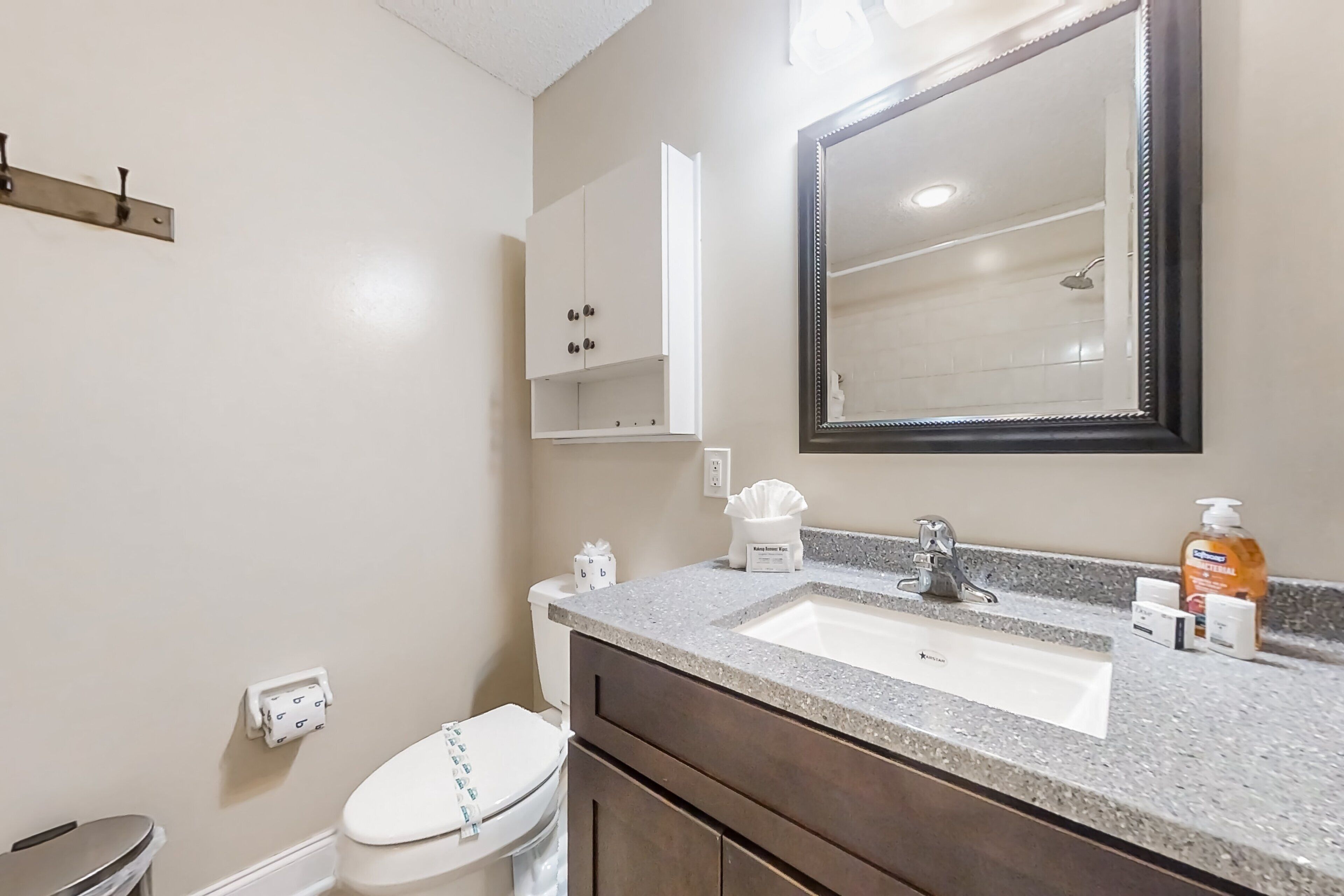 A bathroom with a white toilet, a sink with a mirror above it, and a cabinet above the sink.