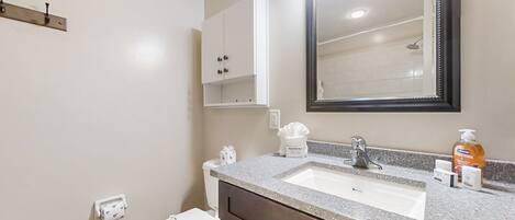 A bathroom with a white toilet, a sink with a mirror above it, and a cabinet above the sink.