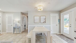 A spacious living area with a wooden table, two framed artworks, and a ceiling light fixture. - Spacious Beach House With Private Pool, Firepit and Enclosed Yard (St. Augustine)