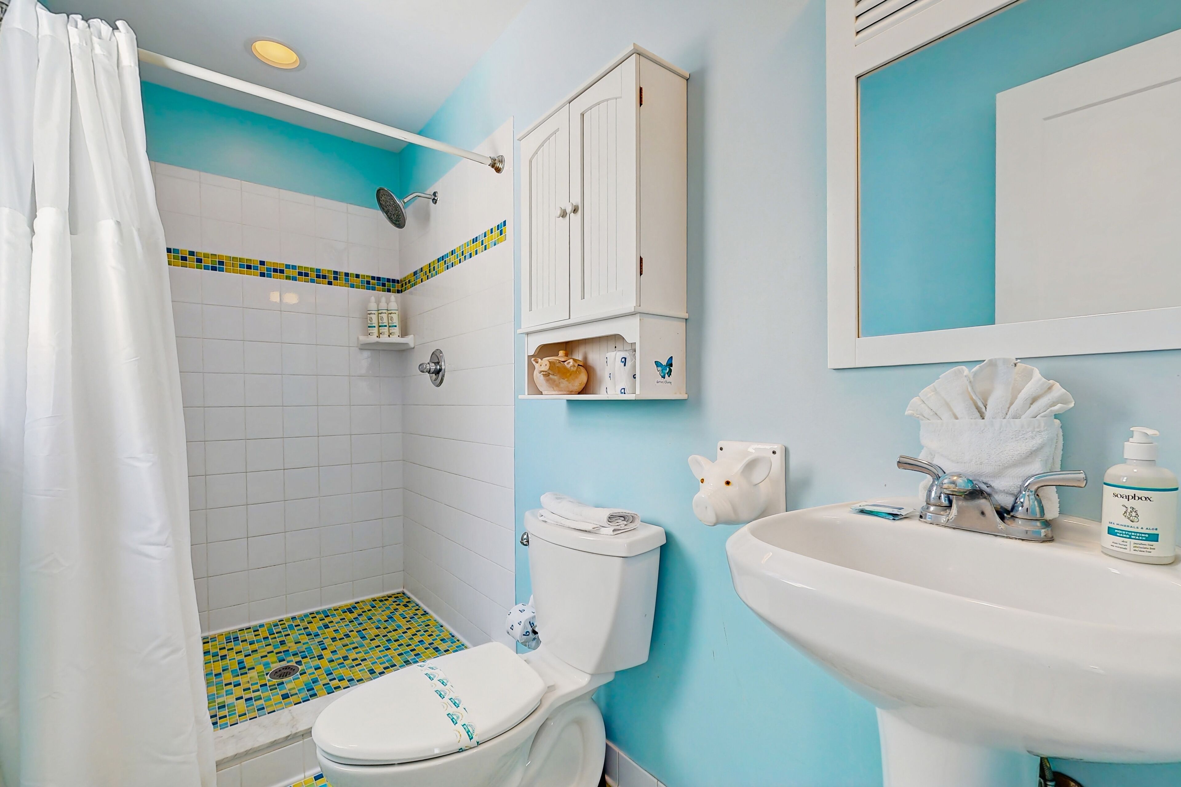 Ein Badezimmer mit Dusche, Toilette, Waschbecken und Schrank.