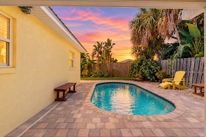Patio con piscina, terraza de madera y cerca de madera.