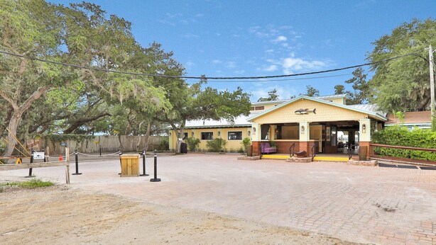 A building with a covered entrance, a dirt path leading to it, and a fenced area with trees. - Oceanfront Home w/ two Kitchens, Furnished Patio & Balcony, & Beach Access (St. Augustine)