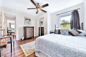 A bedroom with a large bed, a ceiling fan, a dresser, and a window with curtains. - Oceanfront Home w/ two Kitchens, Furnished Patio & Balcony, & Beach Access (St. Augustine)