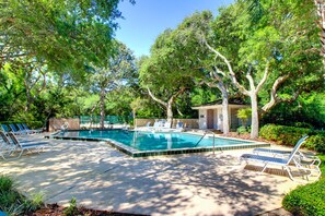 A rectangular swimming pool with a tiled edge, surrounded by lounge chairs and trees. - Renovated Condo With Easy Beach Access, Balcony, Pool & Spectacular Ocean Views (Fernandina Beach)