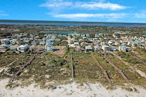 An aerial view of a coastal residential area with houses, a beach, and a railway track. - Serene 2-level Home With Wifi & Deck - Walk to Beach, 1 dog Welcome (St. Augustine)