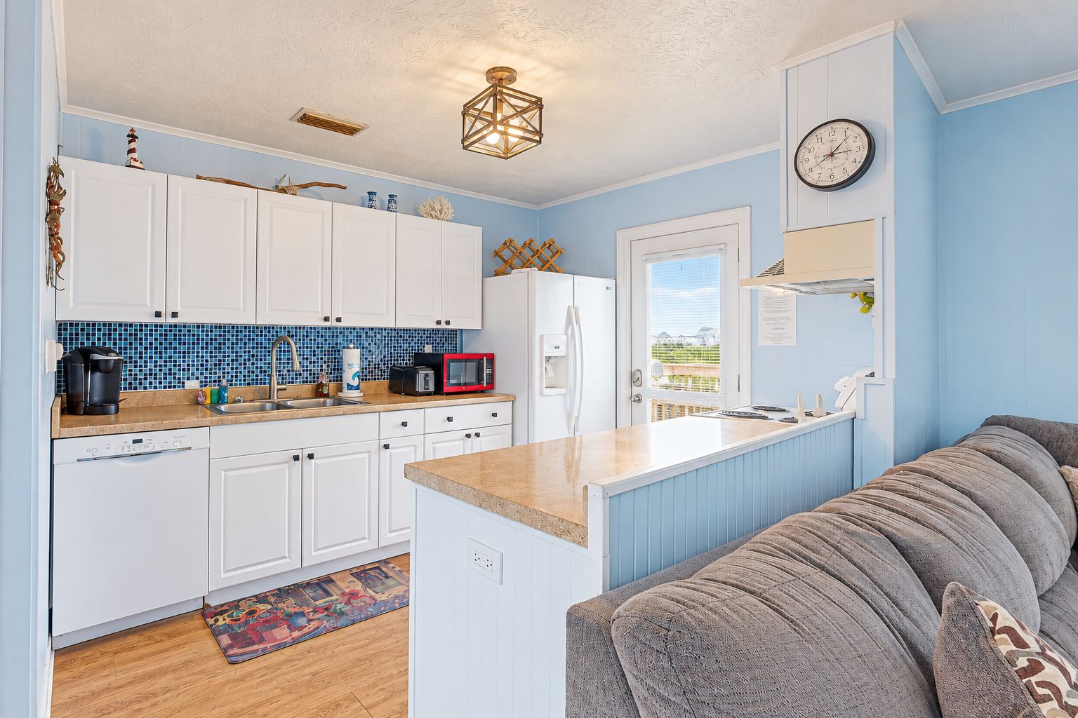 A compact kitchen with white cabinets, a microwave, and a coffee maker. There's a window with a view of the outdoors.