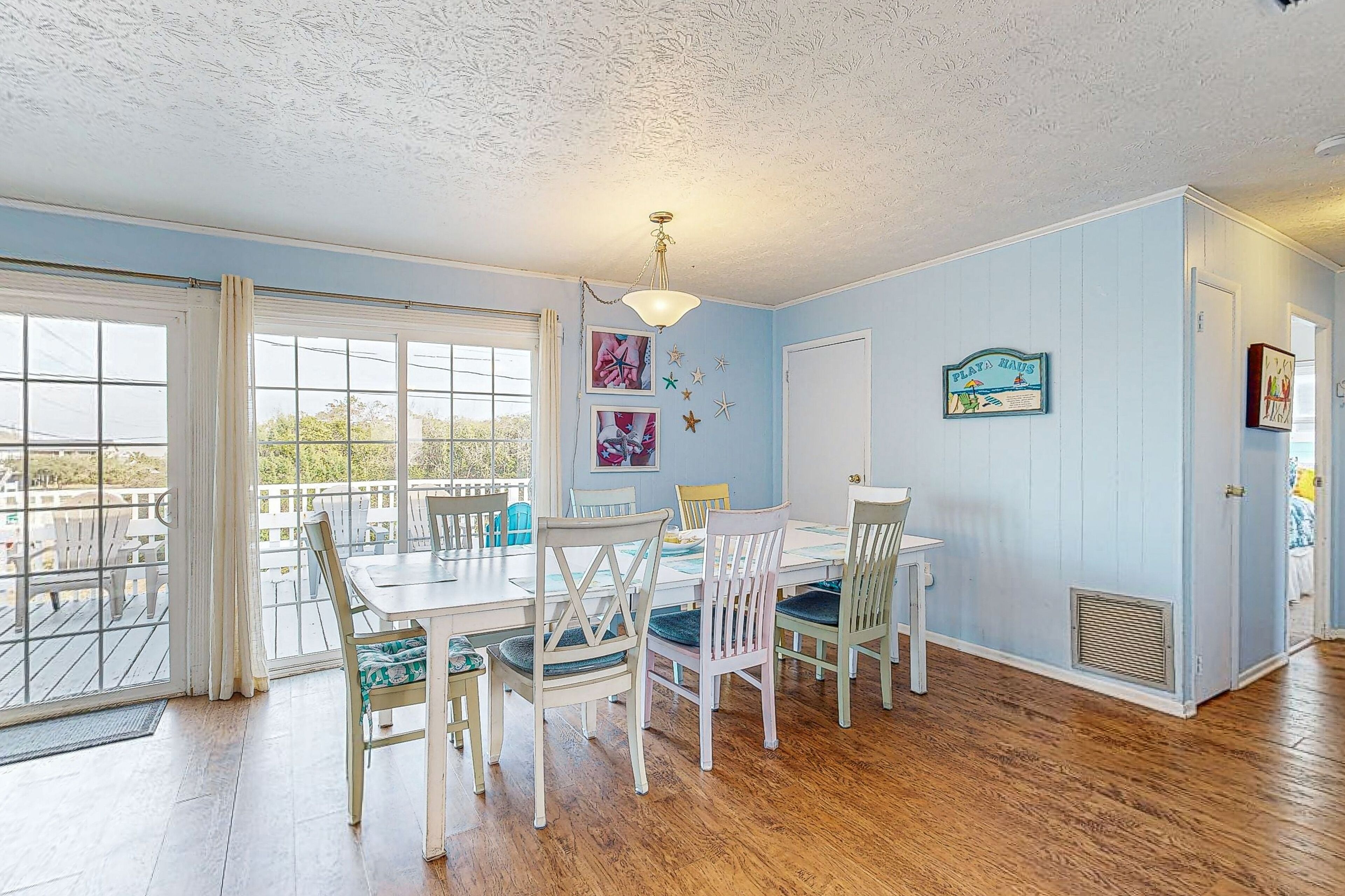 A dining area with a table and chairs, a ceiling fan, and a view through a large window.